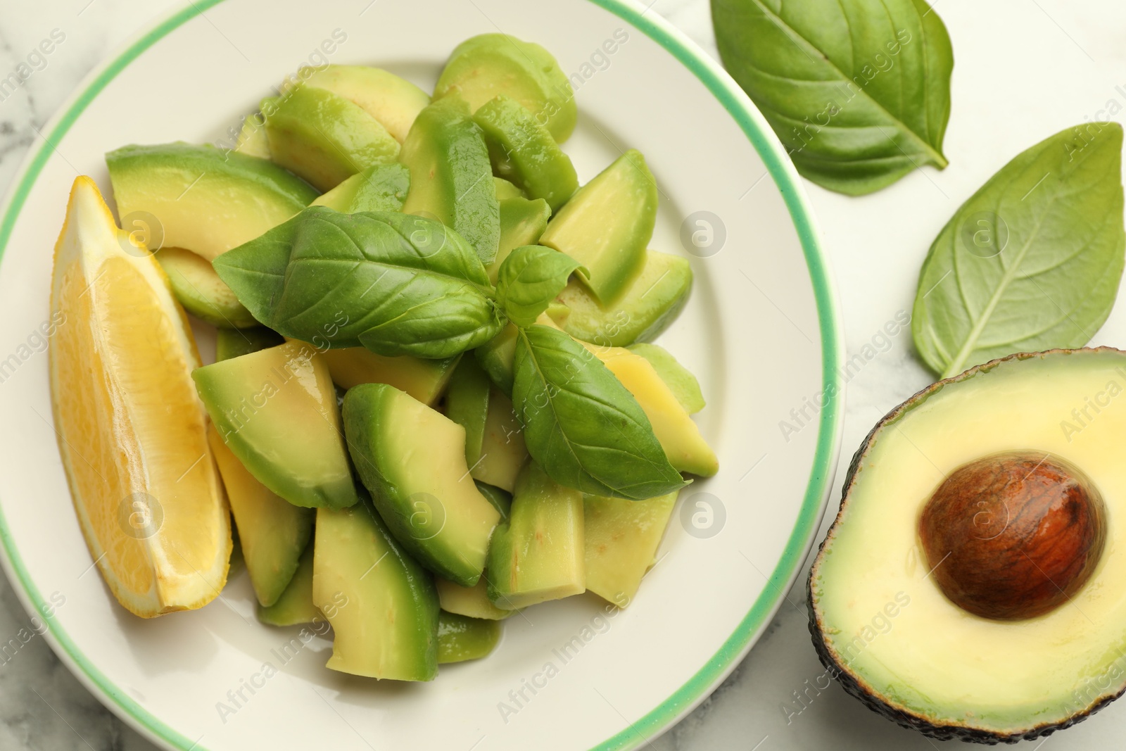 Tasty ripe green avocados, basil and lemon on white marble table, flat lay Photo of Tasty ripe green avocados, basil and lemon on white marble table, flat lay