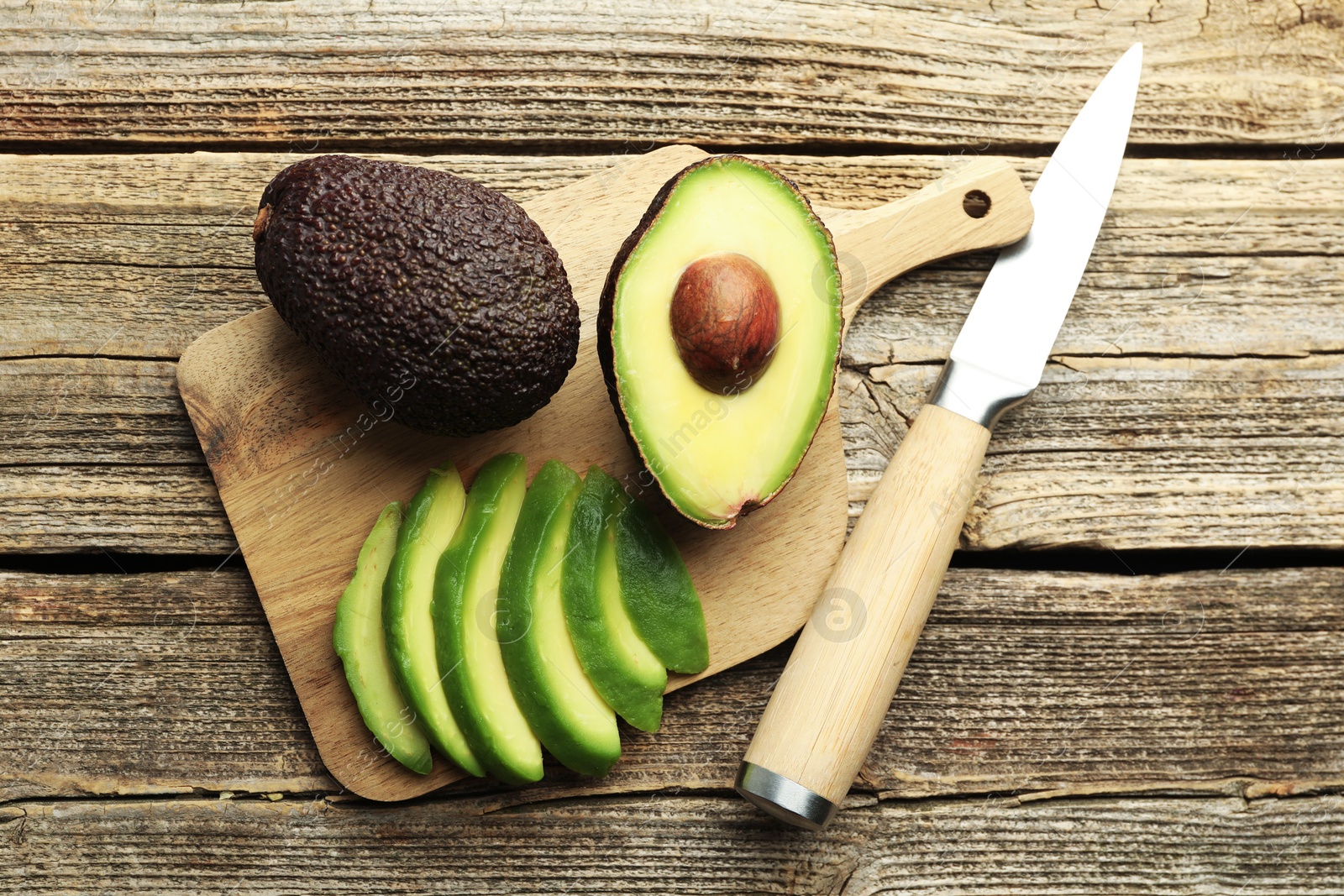 Tasty ripe green avocados and knife on wooden table, flat lay Photo of Tasty ripe green avocados and knife on wooden table, flat lay