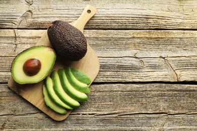 Photo of Tasty ripe green avocados on wooden table, top view. Space for text