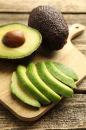Photo of Tasty ripe green avocados on wooden table, closeup