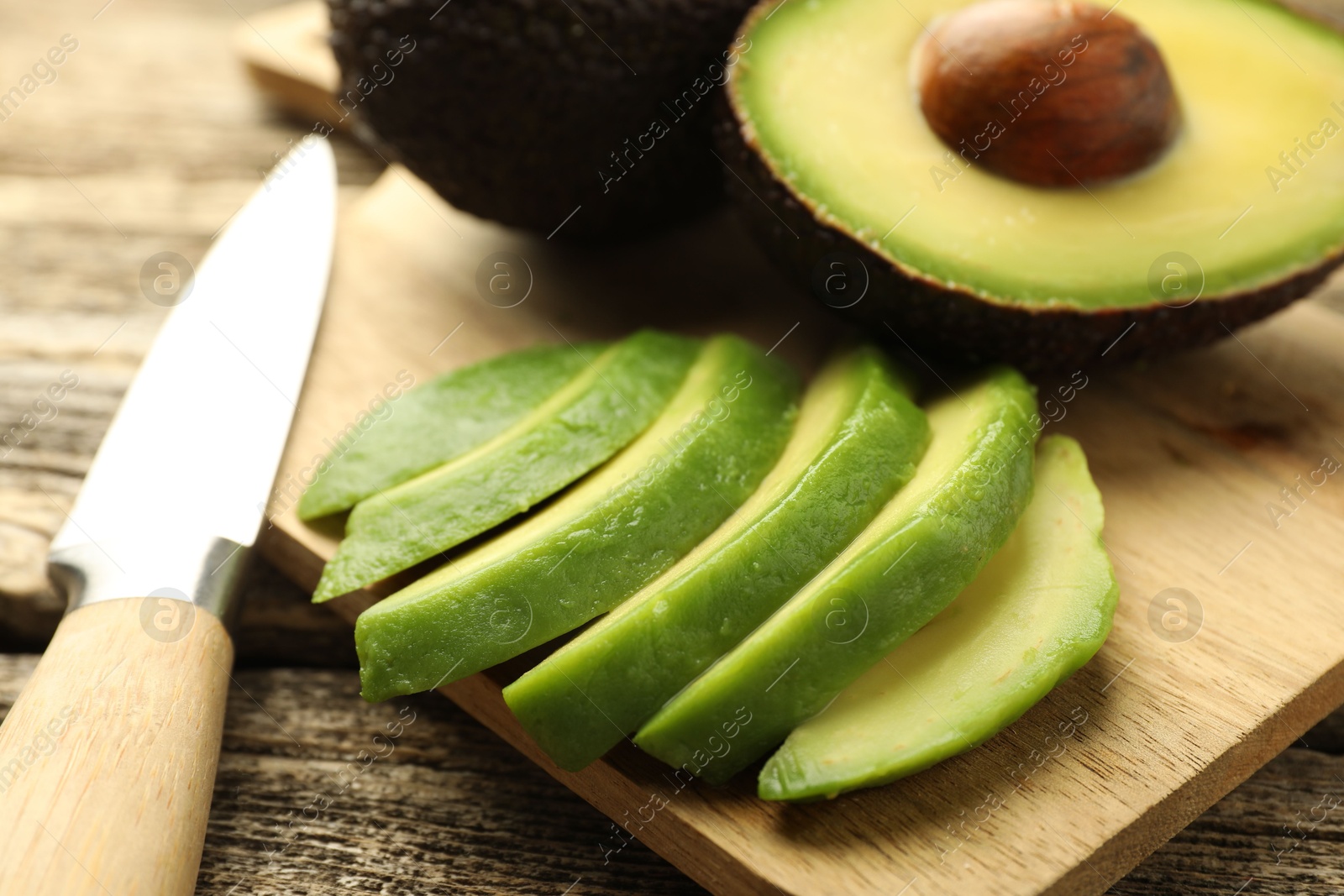Tasty ripe green avocados and knife on wooden table, closeup Photo of Tasty ripe green avocados and knife on wooden table, closeup