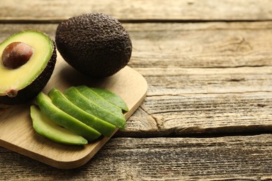 Photo of Tasty ripe green avocados on wooden table, closeup. Space for text