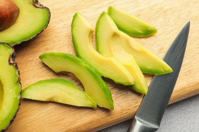 Photo of Cut ripe green avocados and knife on table, top view