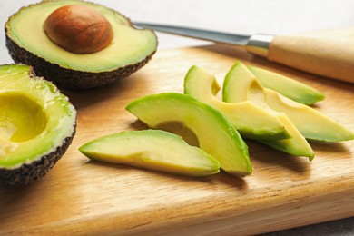 Photo of Cut ripe green avocados and knife on table, closeup