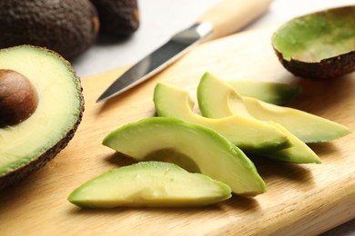 Photo of Cut ripe green avocados and knife on table, closeup