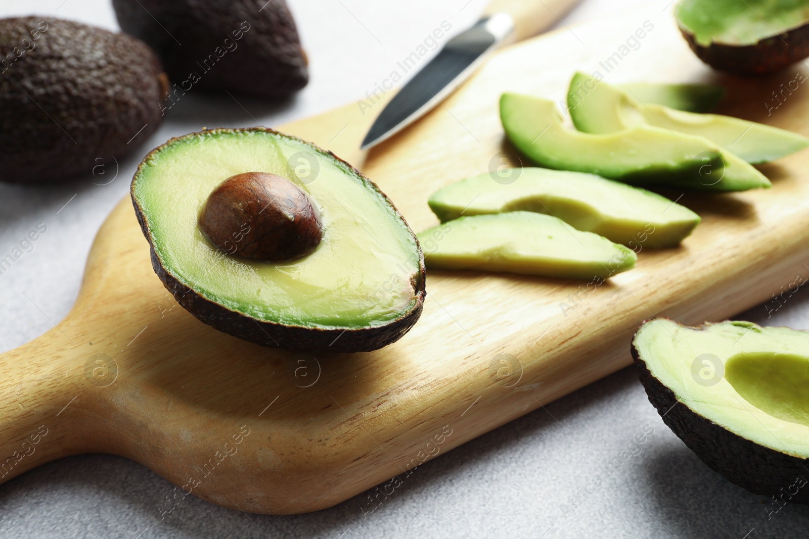 Cut ripe green avocados and knife on light grey table, closeup Photo of Cut ripe green avocados and knife on light grey table, closeup