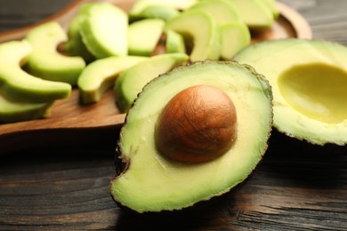 Photo of Cut ripe green avocados on wooden table, closeup