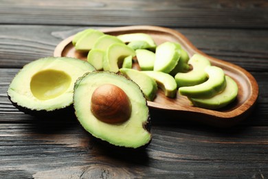 Photo of Cut ripe green avocados on wooden table, closeup
