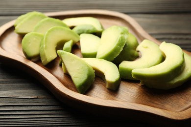 Photo of Cut ripe green avocado on wooden table, closeup
