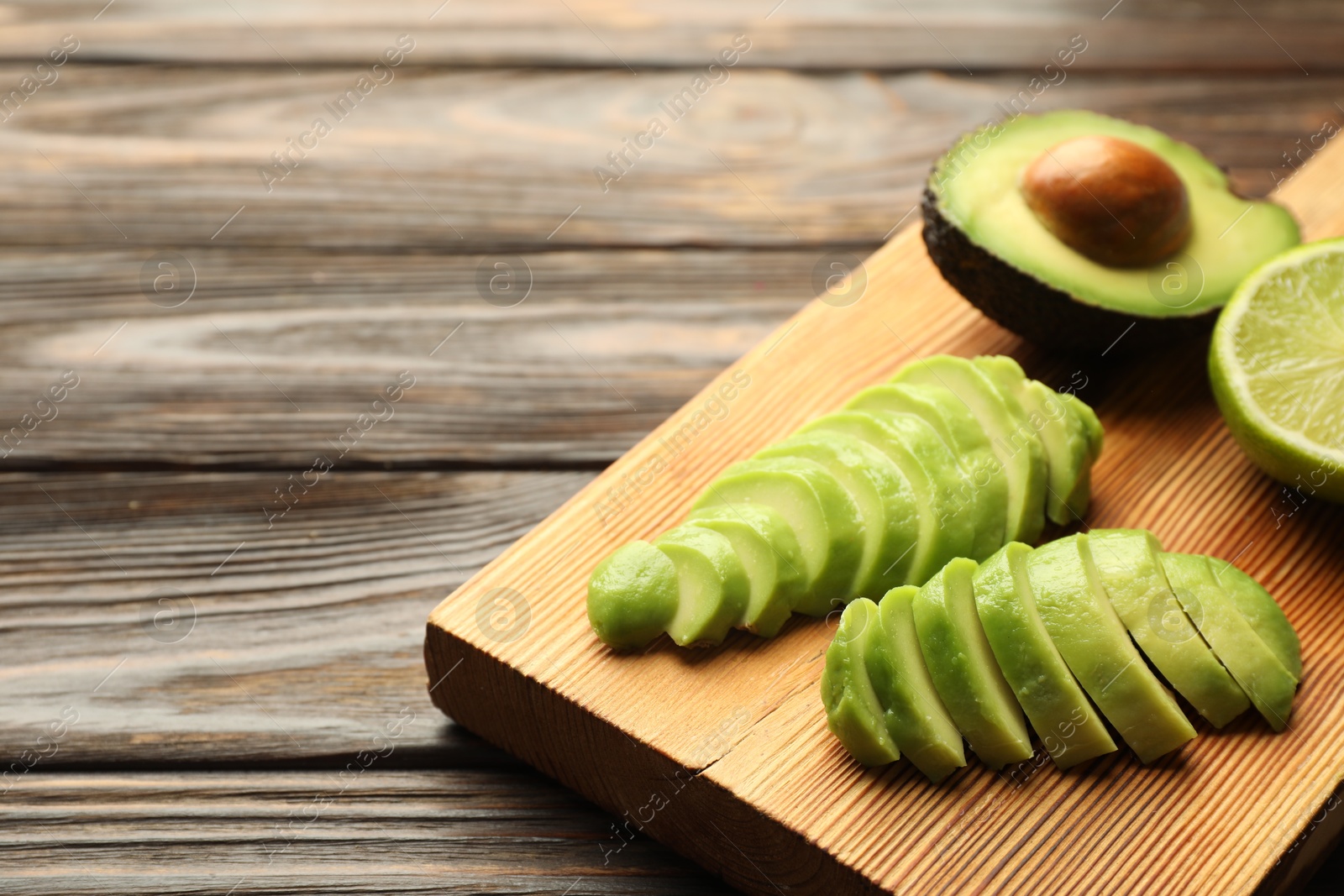 Cut ripe green avocado and lime on wooden table, closeup Photo of Cut ripe green avocado and lime on wooden table, closeup
