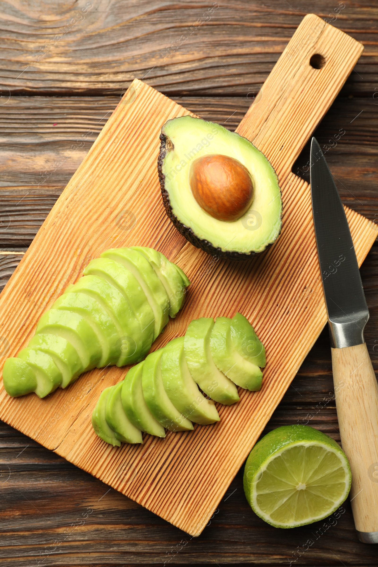Cut ripe green avocado, lime and knife on wooden table, flat lay Photo of Cut ripe green avocado, lime and knife on wooden table, flat lay