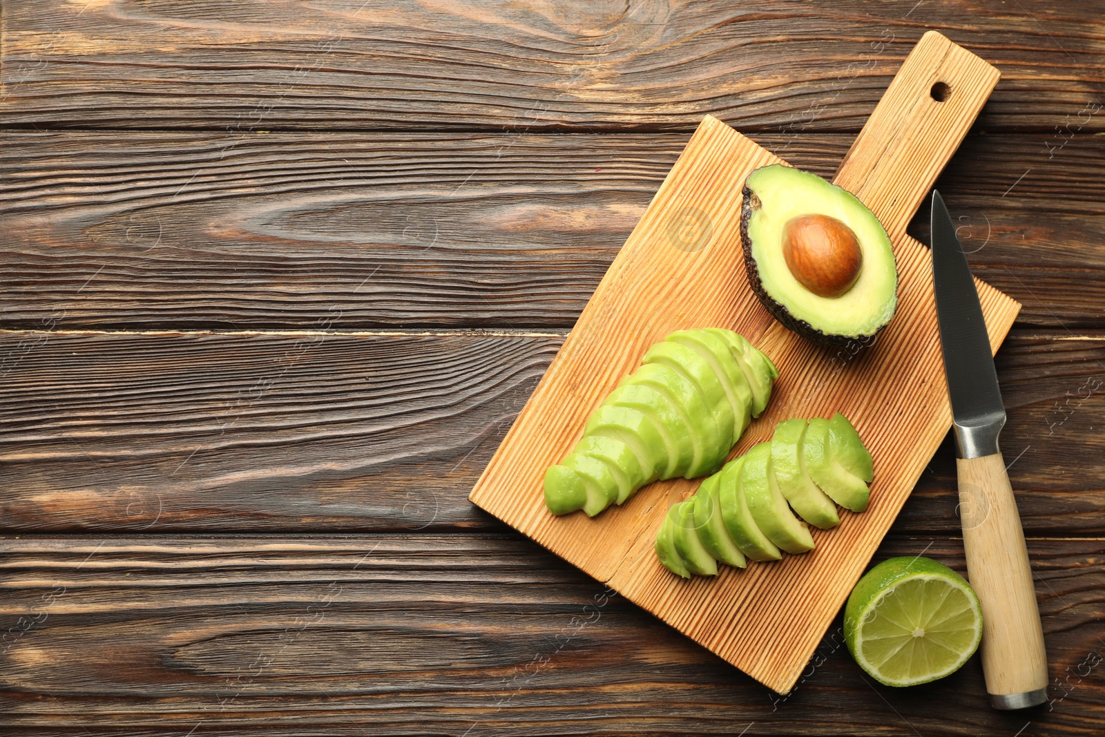 Cut ripe green avocado, lime and knife on wooden table, flat lay. Space for text Photo of Cut ripe green avocado, lime and knife on wooden table, flat lay. Space for text