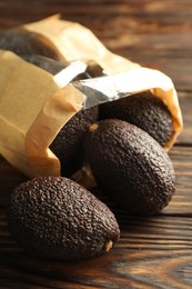 Photo of Ripe avocado fruits in paper package on wooden table, closeup