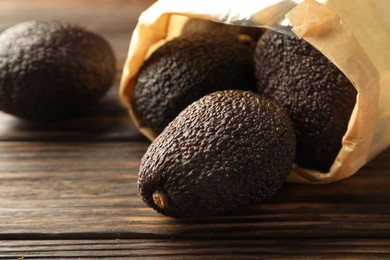 Photo of Ripe avocado fruits in paper package on wooden table, closeup