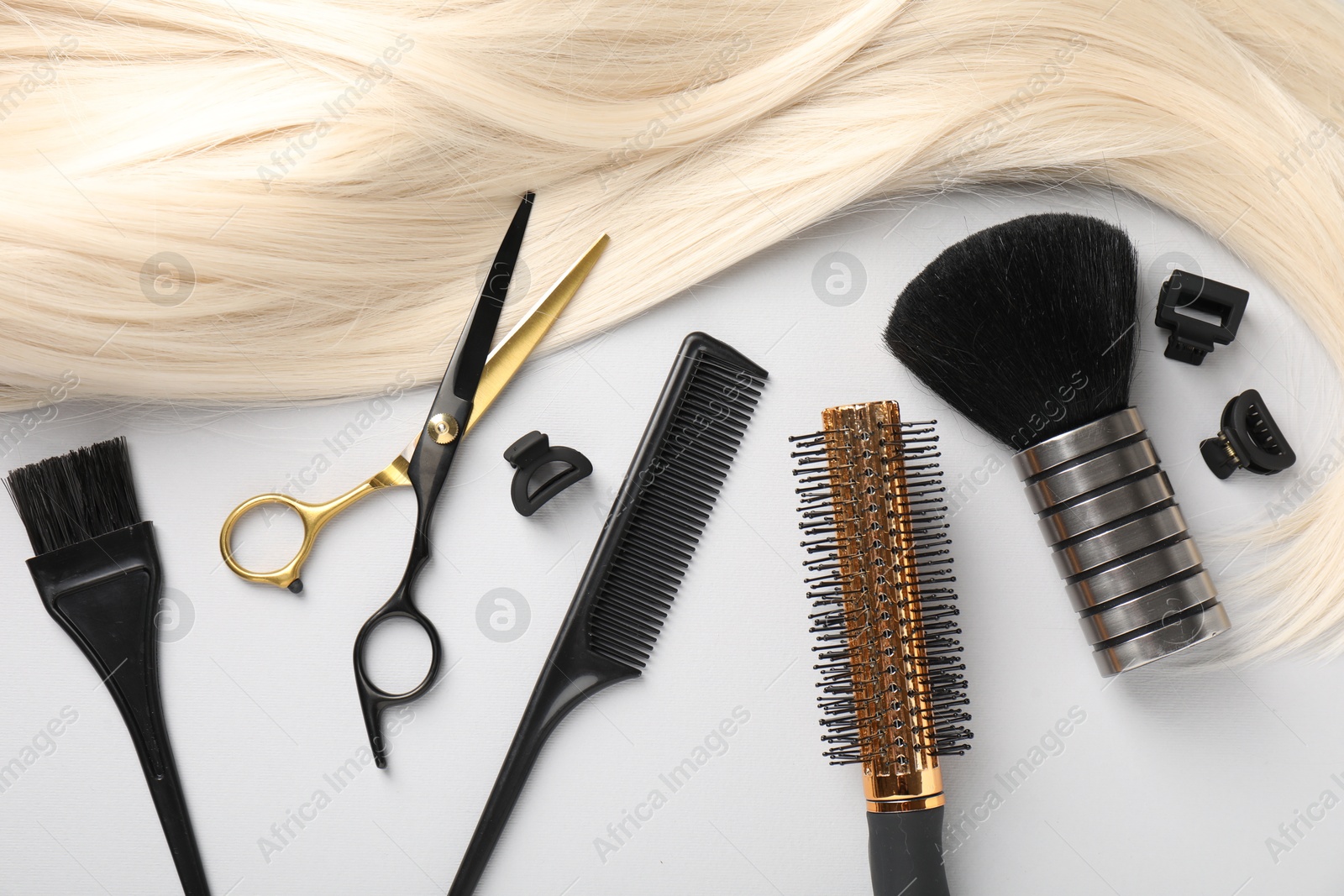 Different hairdresser's tools and blonde hair lock on light grey background, flat lay Photo of Different hairdresser's tools and blonde hair lock on light grey background, flat lay