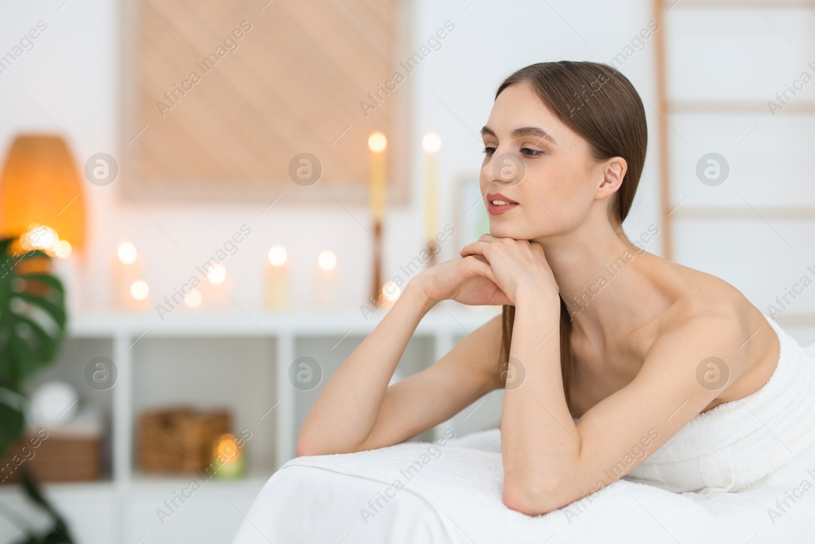 Beautiful woman relaxing on massage couch in spa salon. Space for text Photo of Beautiful woman relaxing on massage couch in spa salon. Space for text