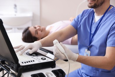 Photo of Sonographer with ultrasound transducer and woman waiting for examination in clinic, selective focus