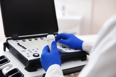 Photo of Sonographer with transducer and ultrasound machine in clinic, closeup