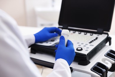 Photo of Sonographer with transducer and ultrasound machine in clinic, closeup