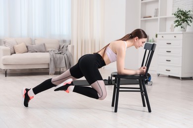 Photo of Beautiful woman exercising with chair at home