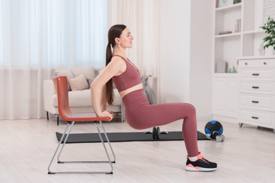 Photo of Beautiful woman exercising with chair at home