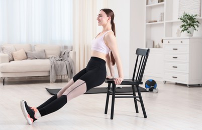 Photo of Beautiful woman exercising with chair at home
