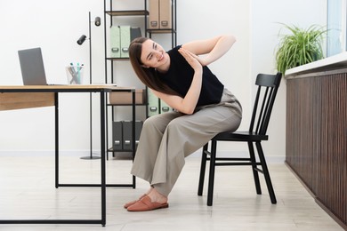 Photo of Beautiful woman stretching on chair in office