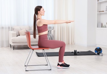 Photo of Beautiful woman stretching on chair at home