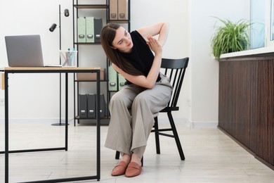 Photo of Beautiful woman stretching on chair in office