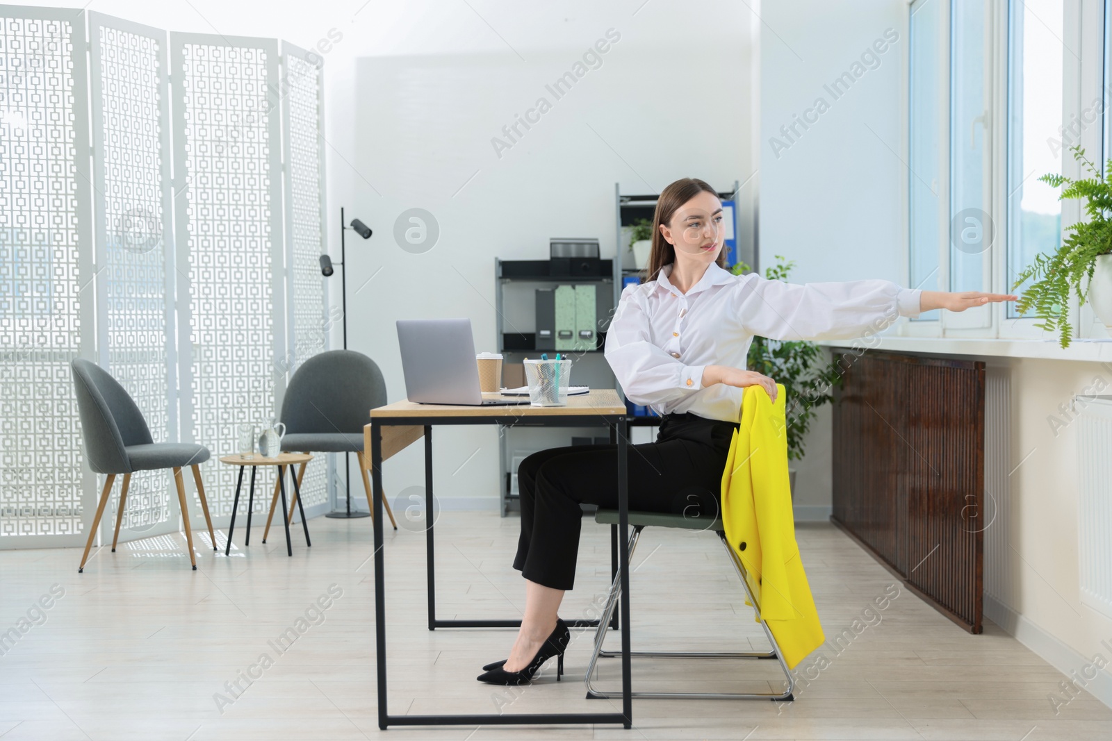 Beautiful woman stretching on chair in office Photo of Beautiful woman stretching on chair in office