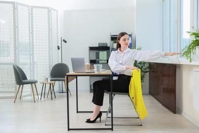 Photo of Beautiful woman stretching on chair in office