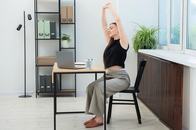 Photo of Beautiful woman stretching on chair in office