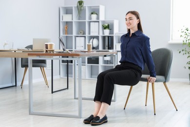 Photo of Beautiful woman exercising with chair in office