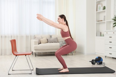 Photo of Beautiful woman exercising on fitness mat at home