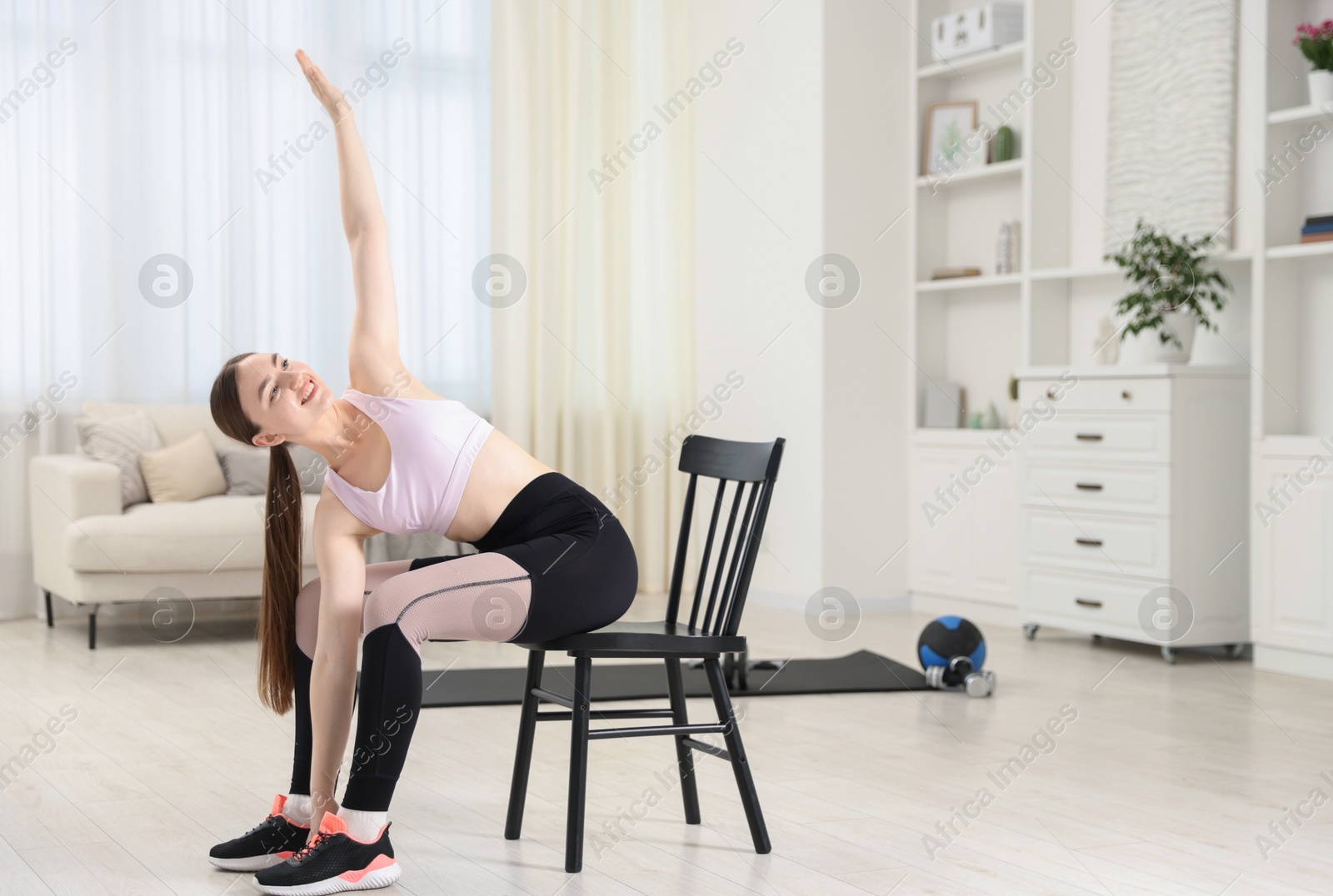 Beautiful woman stretching on chair at home, space for text Photo of Beautiful woman stretching on chair at home, space for text