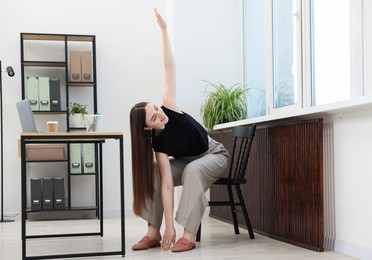 Photo of Beautiful woman stretching on chair in office