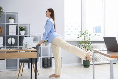 Photo of Beautiful woman exercising with chair in office
