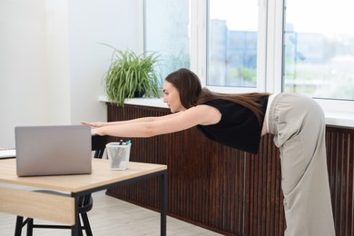 Photo of Beautiful woman exercising with chair in office
