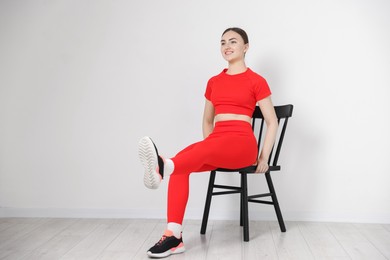 Photo of Beautiful woman stretching on chair at home, space for text