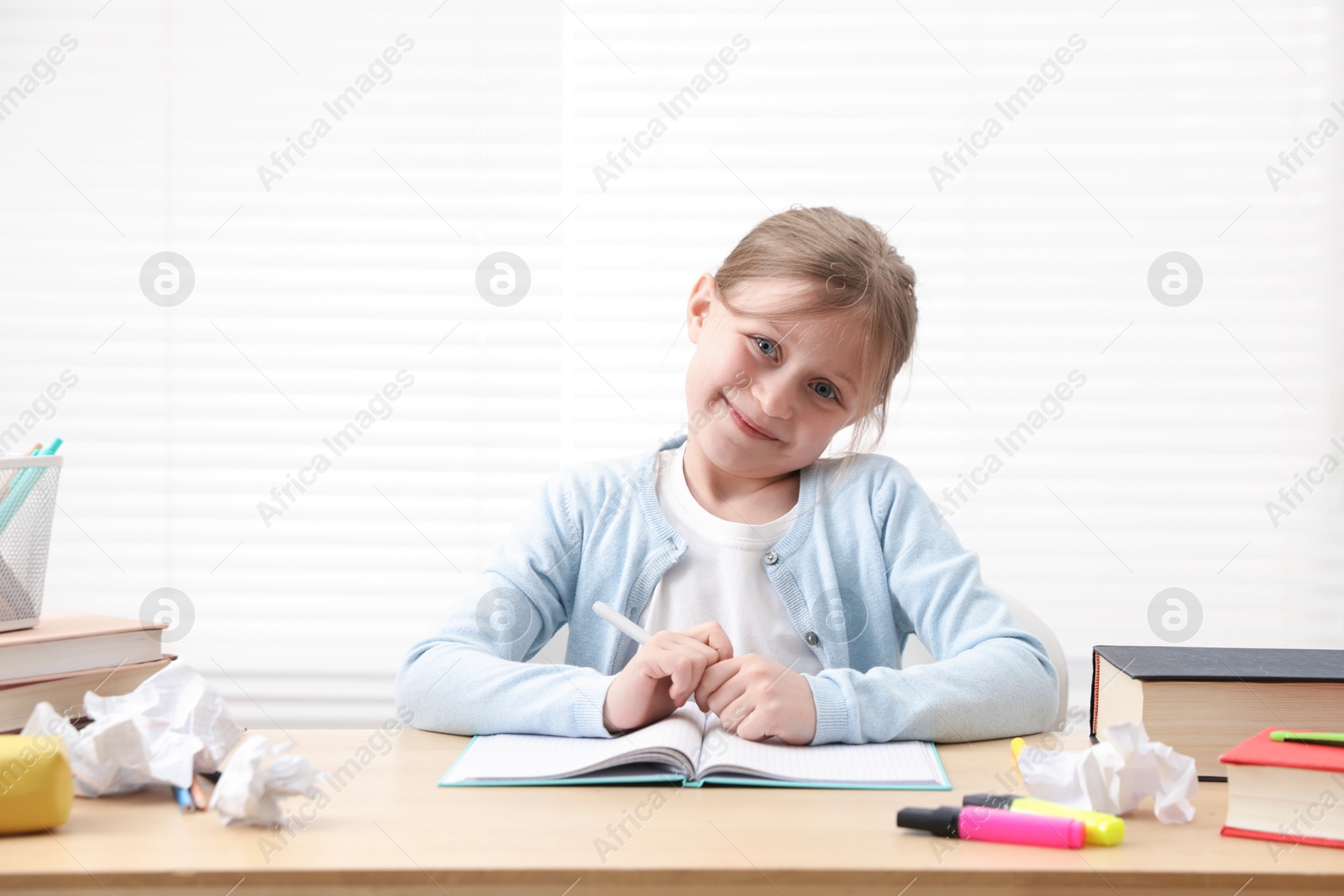 Little girl doing homework at table indoors Photo of Little girl doing homework at table indoors