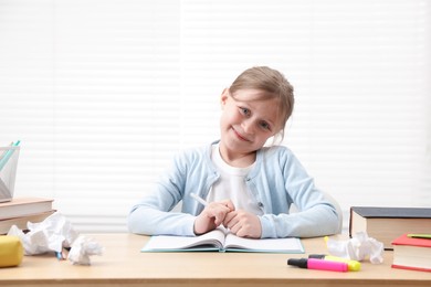 Photo of Little girl doing homework at table indoors