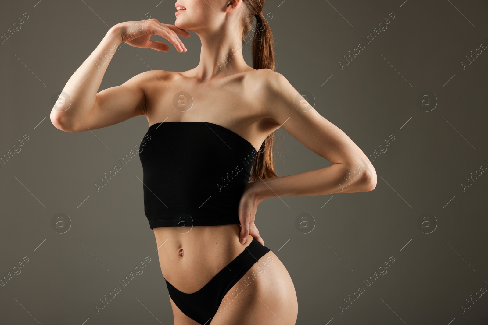 Woman with perfect slim body on grey background, closeup Photo of Woman with perfect slim body on grey background, closeup