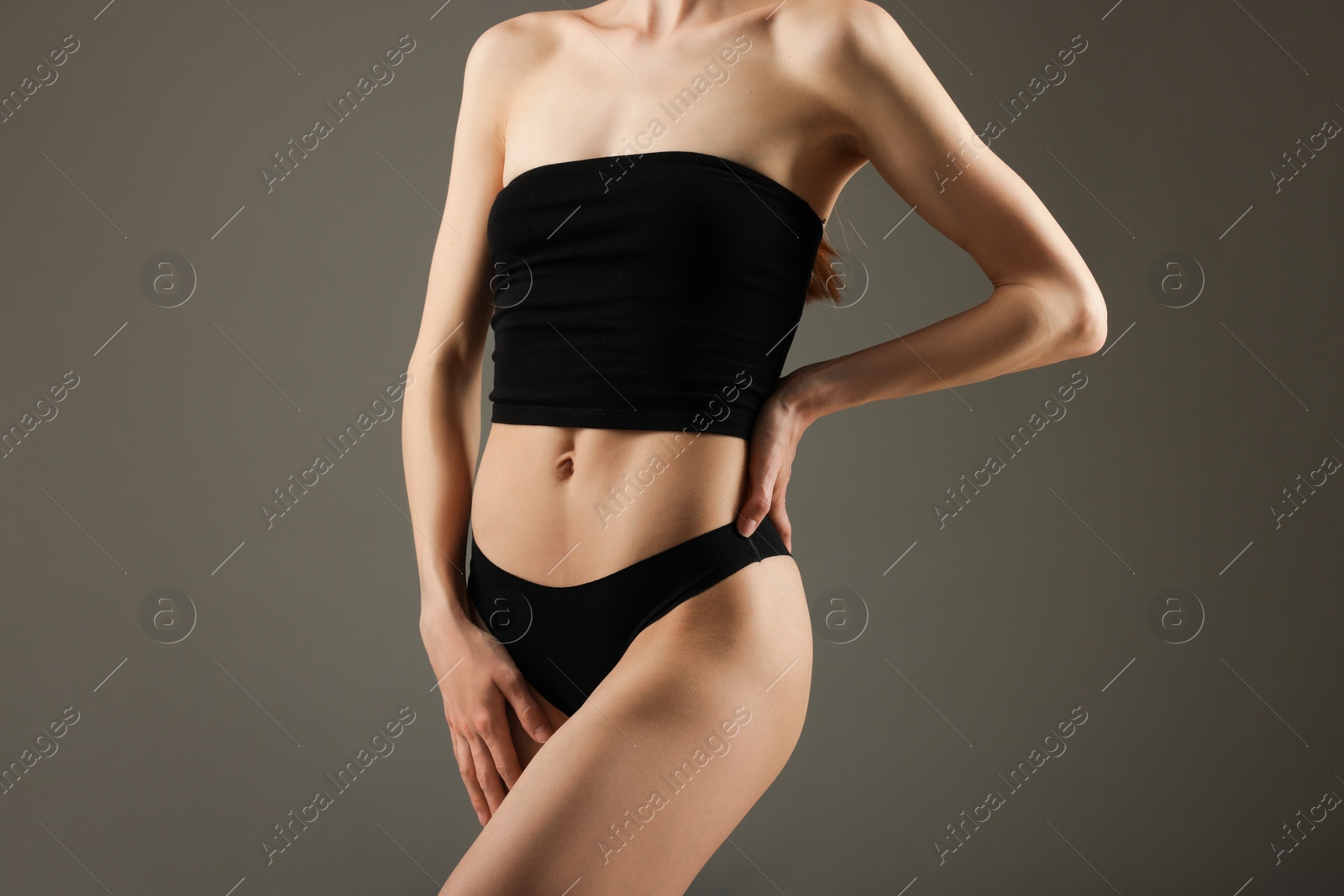 Woman with perfect slim body on grey background, closeup Photo of Woman with perfect slim body on grey background, closeup