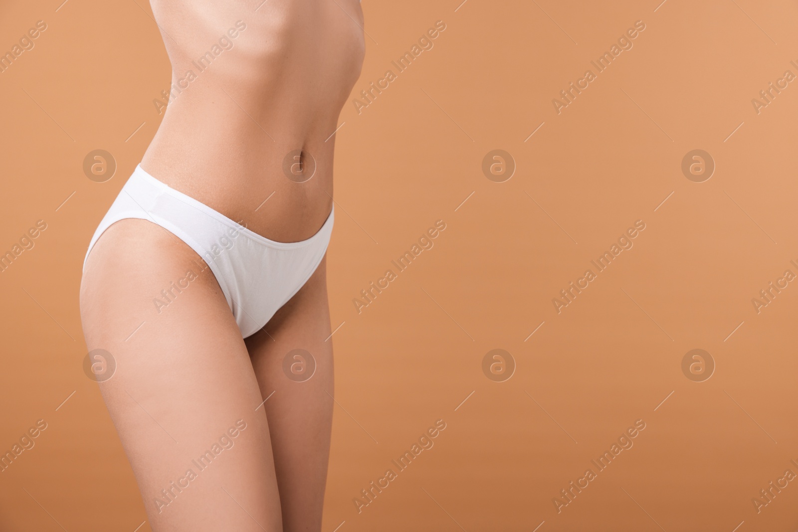 Woman with perfect slim body on beige background, closeup. Space for text Photo of Woman with perfect slim body on beige background, closeup. Space for text