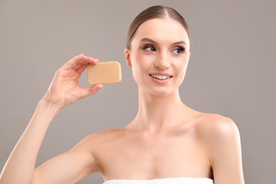Photo of Smiling woman with soap bar on grey background