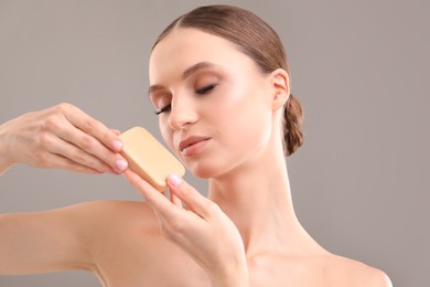 Photo of Beautiful woman with soap bar on grey background, closeup