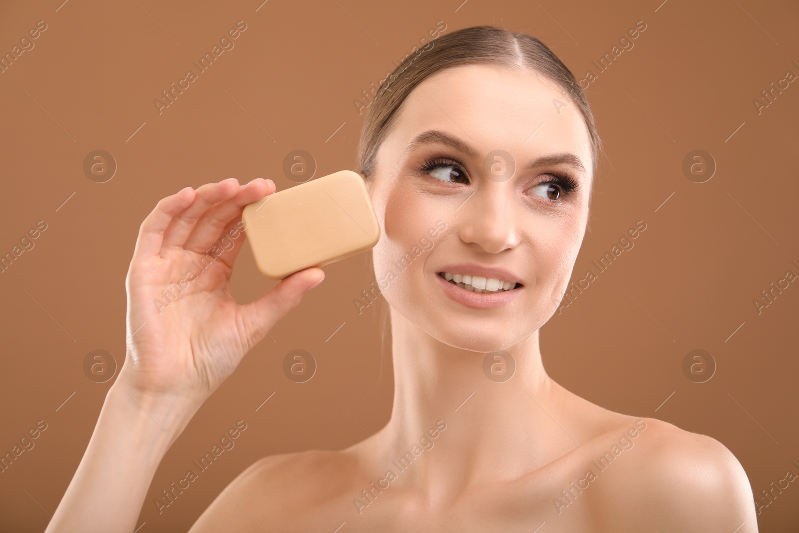 Smiling woman with soap bar on brown background, closeup Photo of Smiling woman with soap bar on brown background, closeup