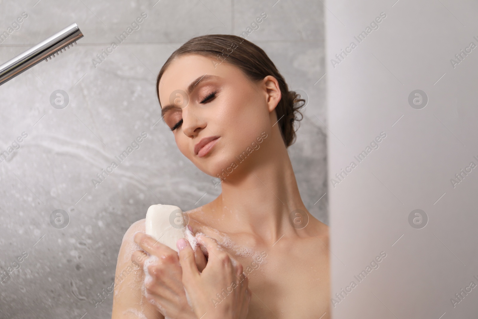 Woman washing body with soap bar in bathroom Photo of Woman washing body with soap bar in bathroom