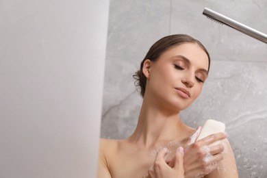 Photo of Woman washing body with soap bar in bathroom. Space for text