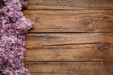 Photo of Beautiful lilac flowers on wooden table, flat lay. Space for text